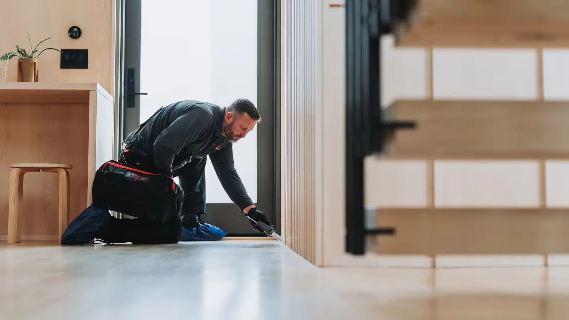 An A&A technician applying cockroach gel bait along a baseboard