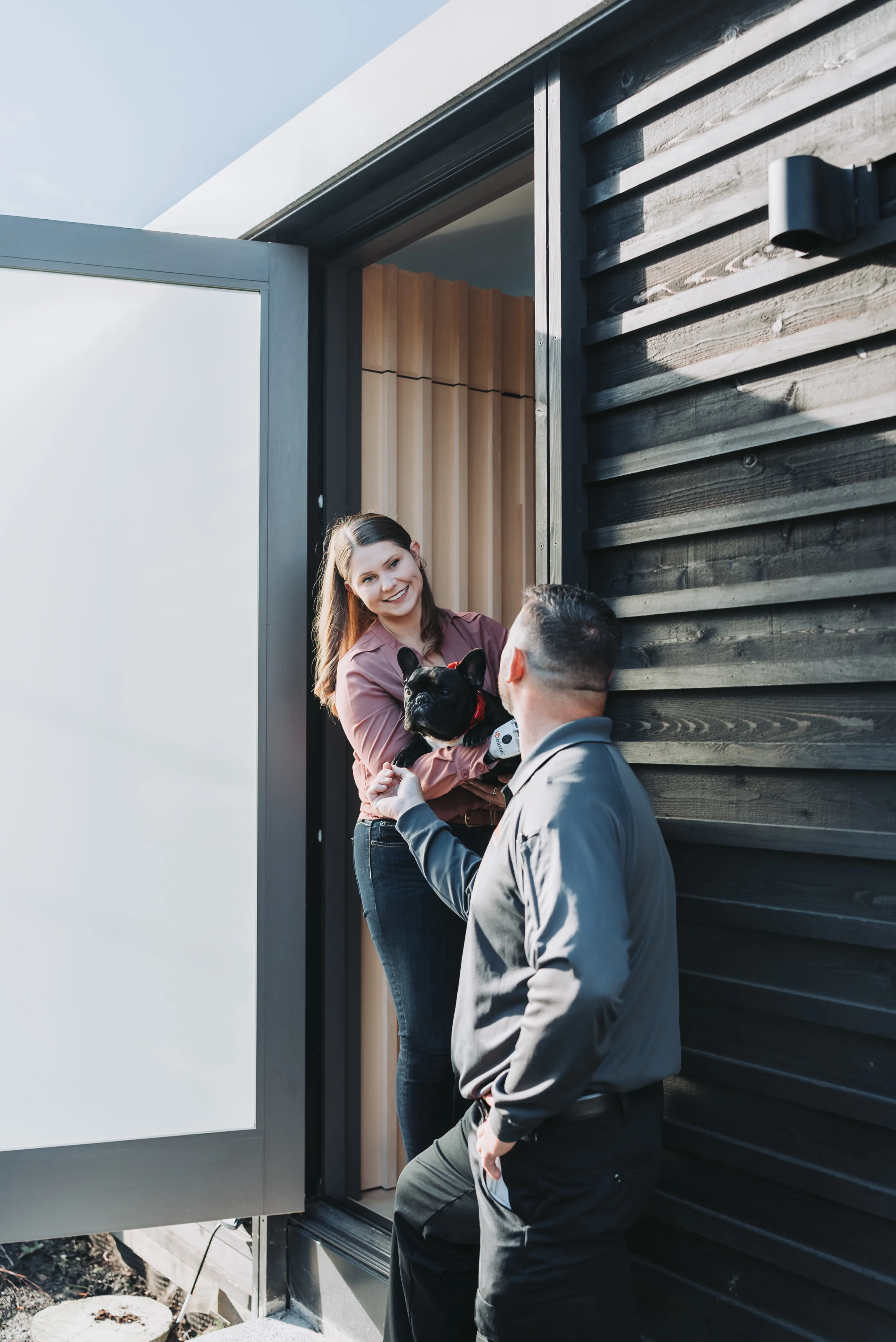 An A&A Pest Control technician arriving at a customer's front door as she holds her French bulldog, Lola
