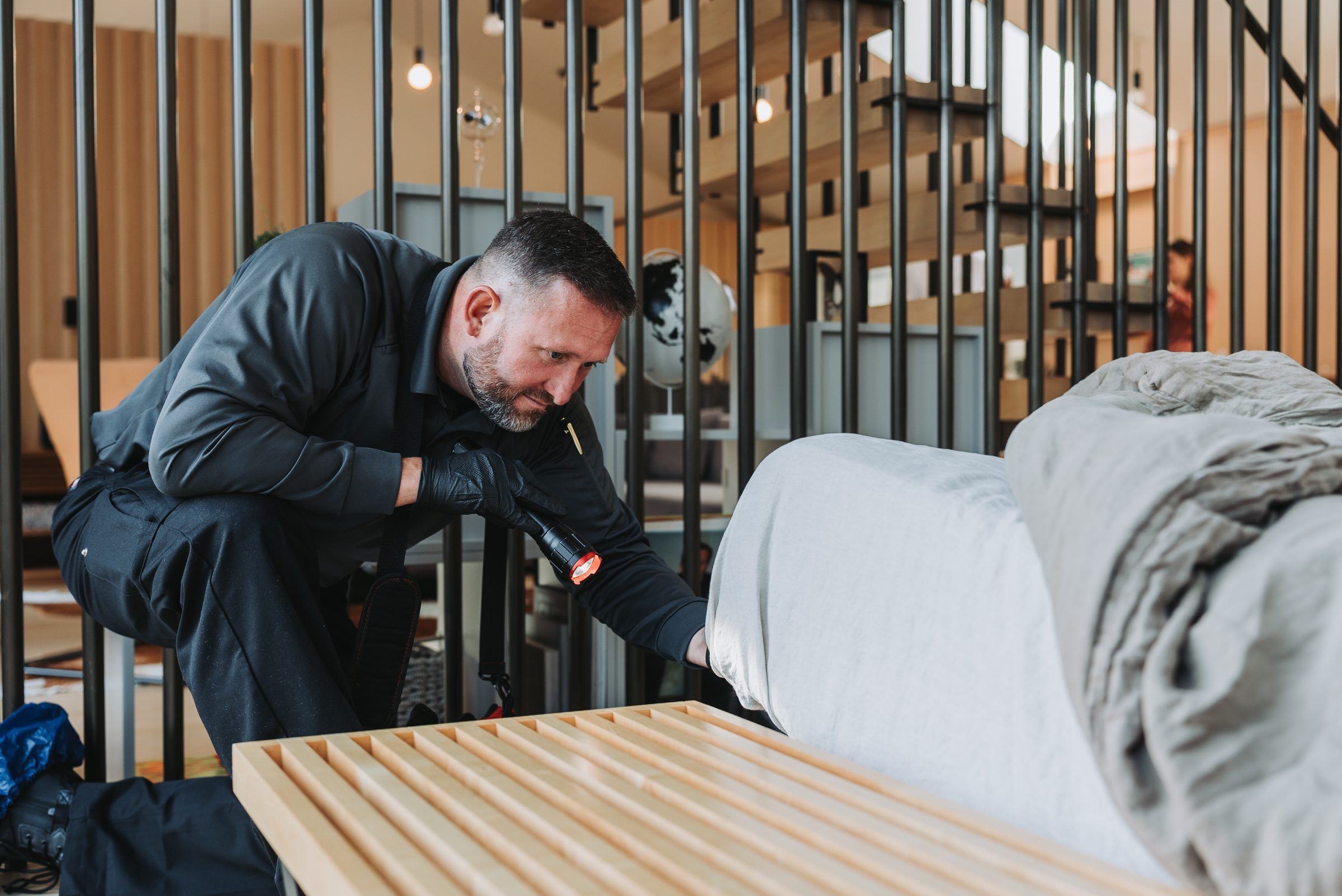 An A&A technician kneeling to inspect the frame of a bed for bed bugs