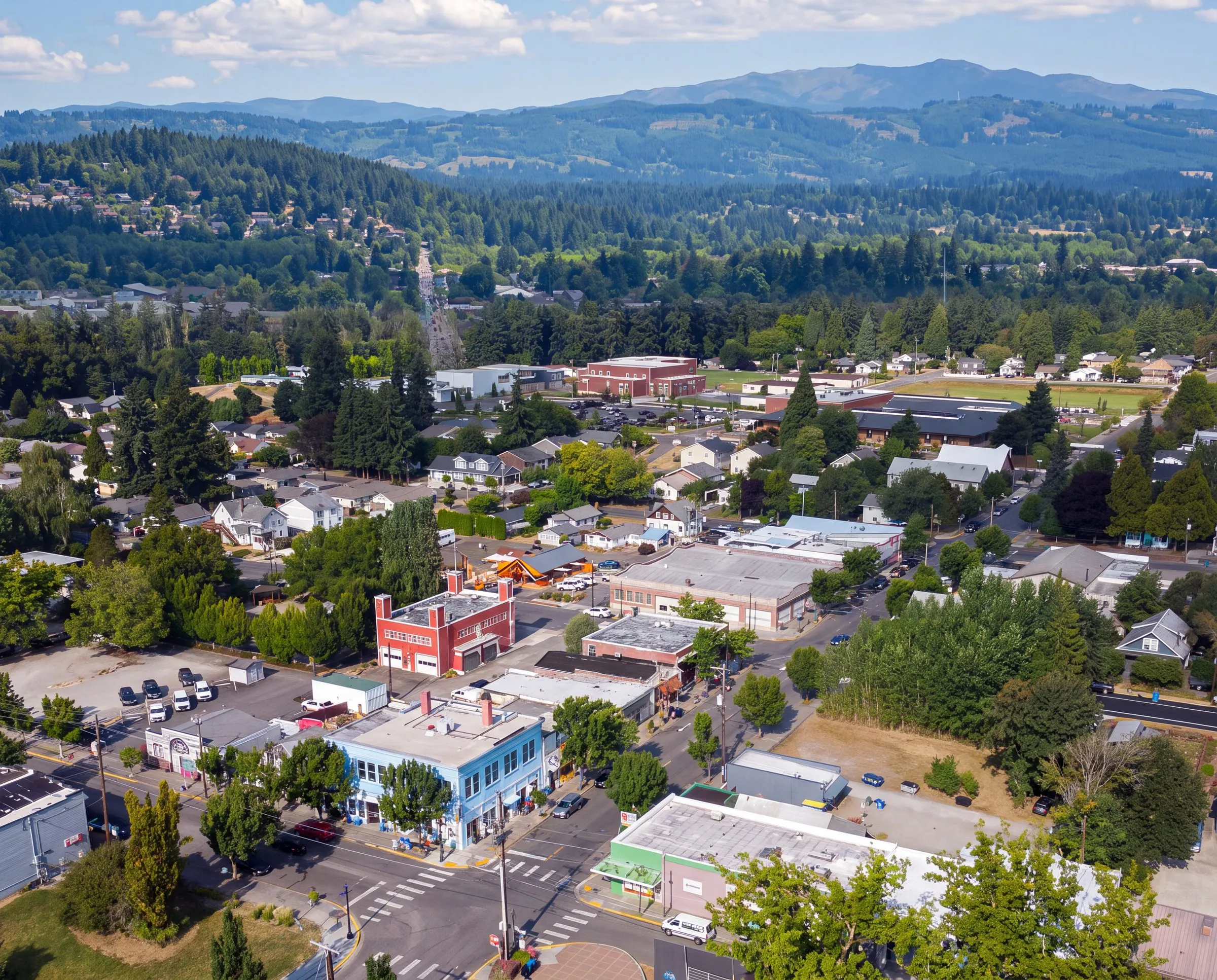 An aerial view of downtown Battle Ground, Washington, with forested hills and mountains beyond