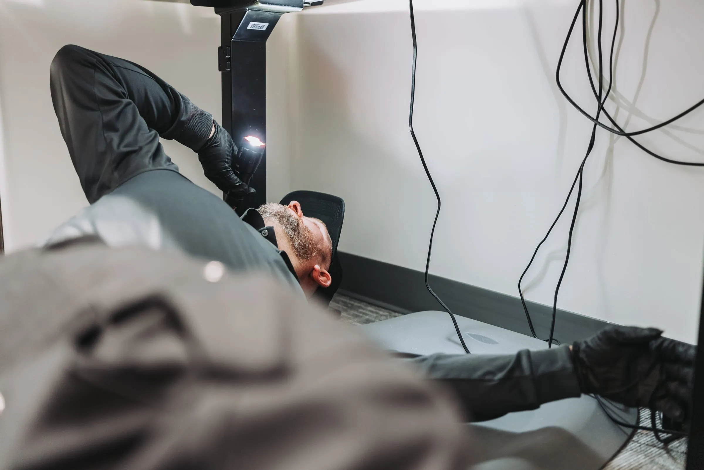 An A&A technician inspecting under a desk with a flashlight