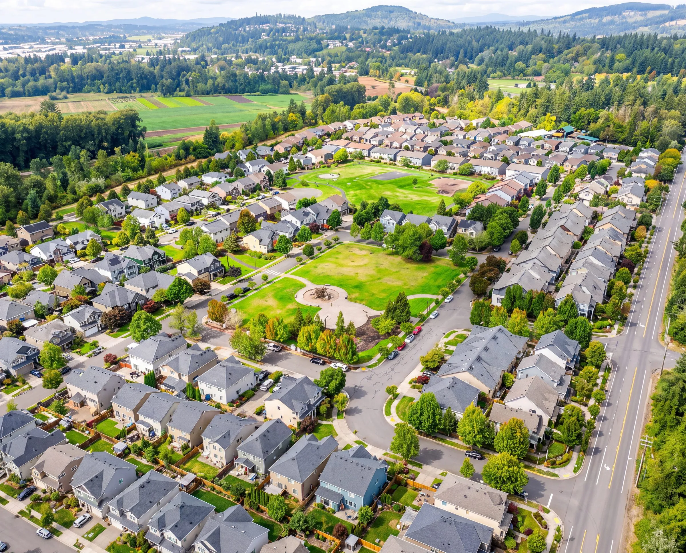 An aerial view of a neighborhood and park in Damascus, Oregon, with farmland and hills beyond