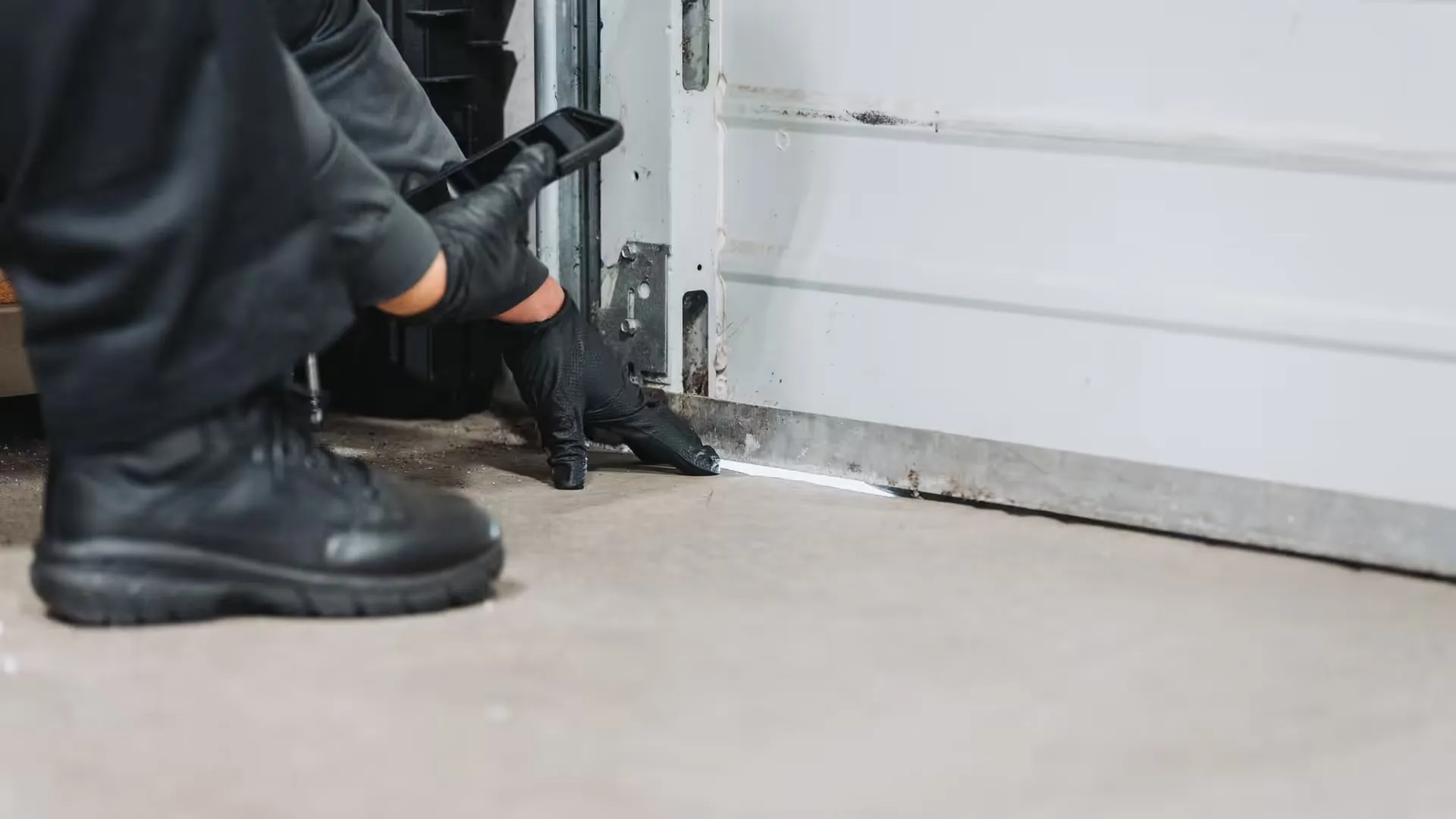 An A&A technician checking the gap under a garage door for rodent entry points