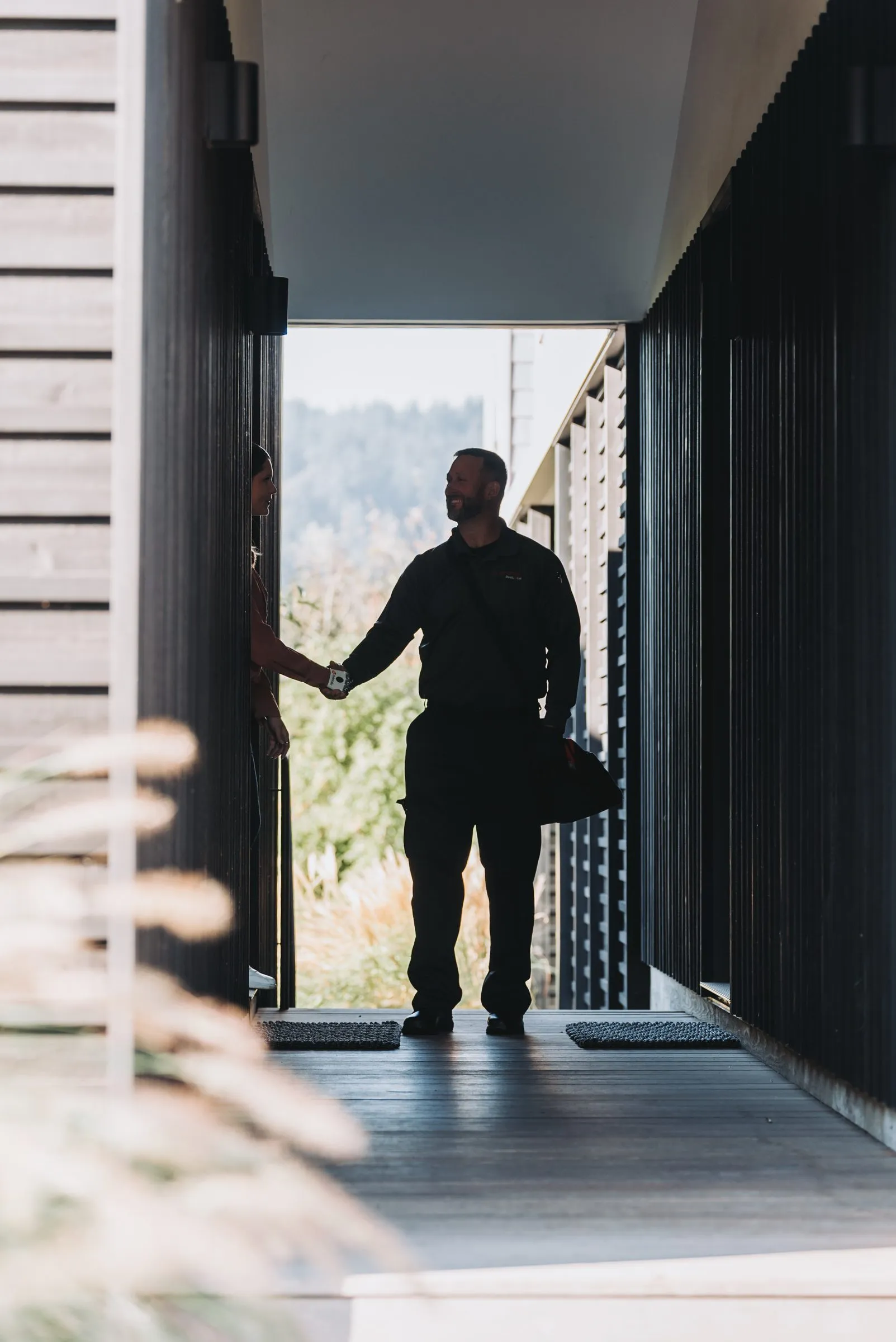 An A&A technician shaking hands with a customer at the front door on his way out