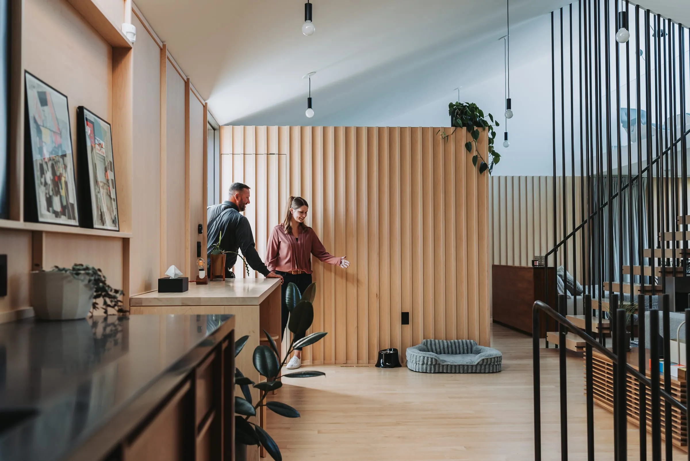 An A&A technician talking with a homeowner beside a dog bed in a bright living room