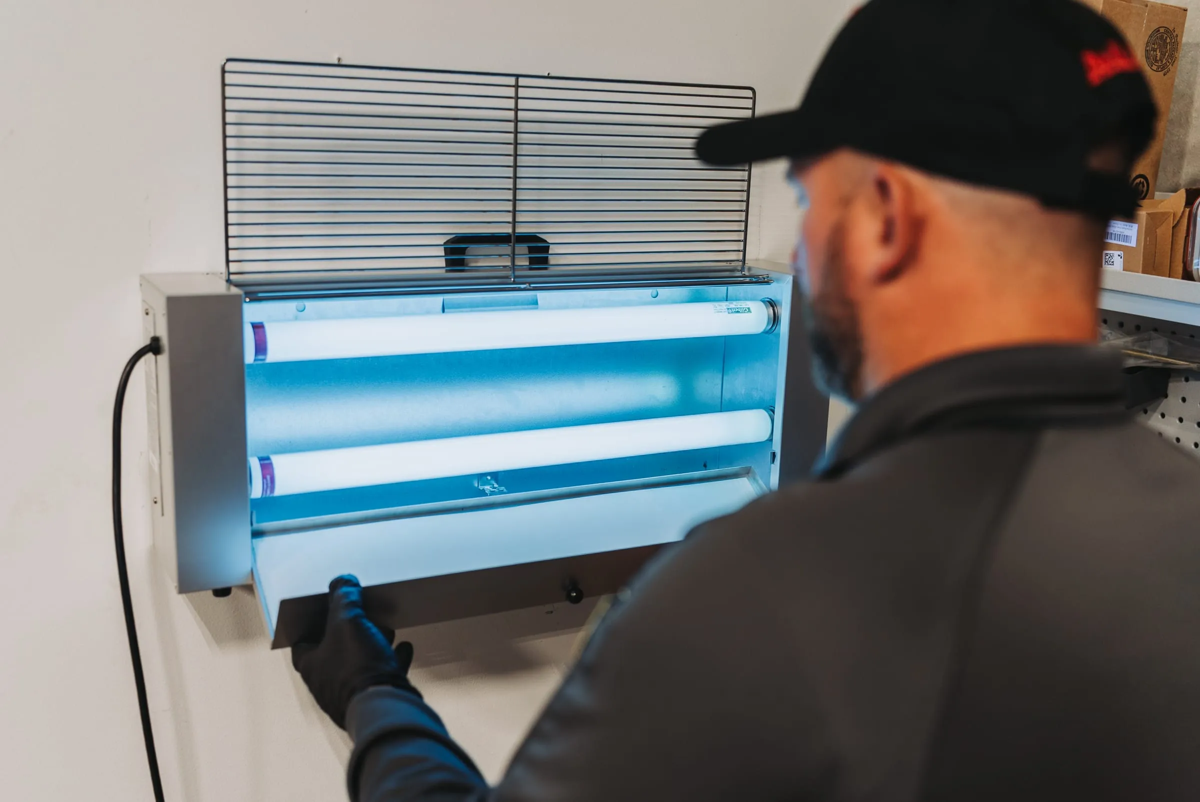 An A&A technician servicing a wall-mounted insect light trap