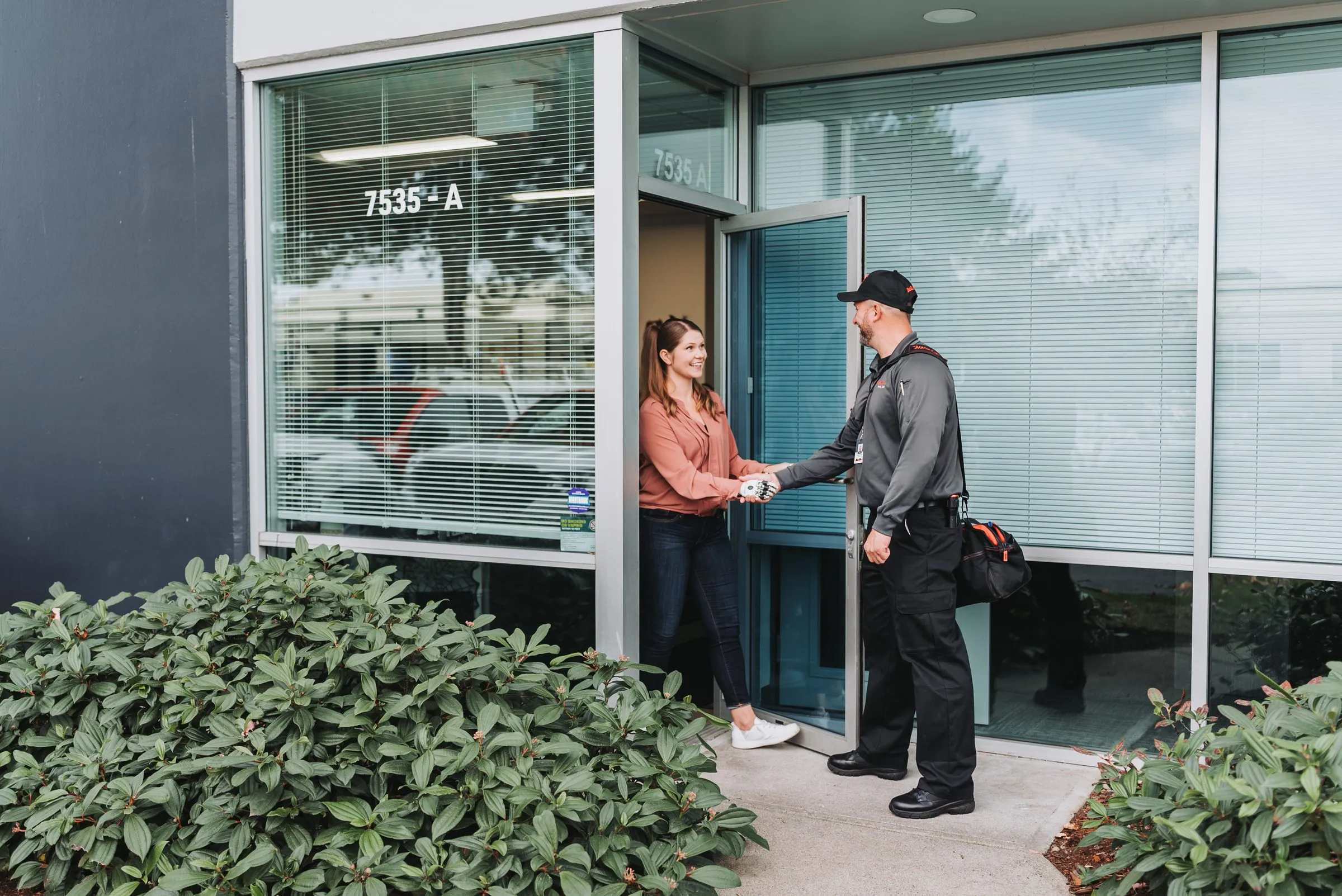 An A&A technician shaking hands with a facility manager at an office entrance