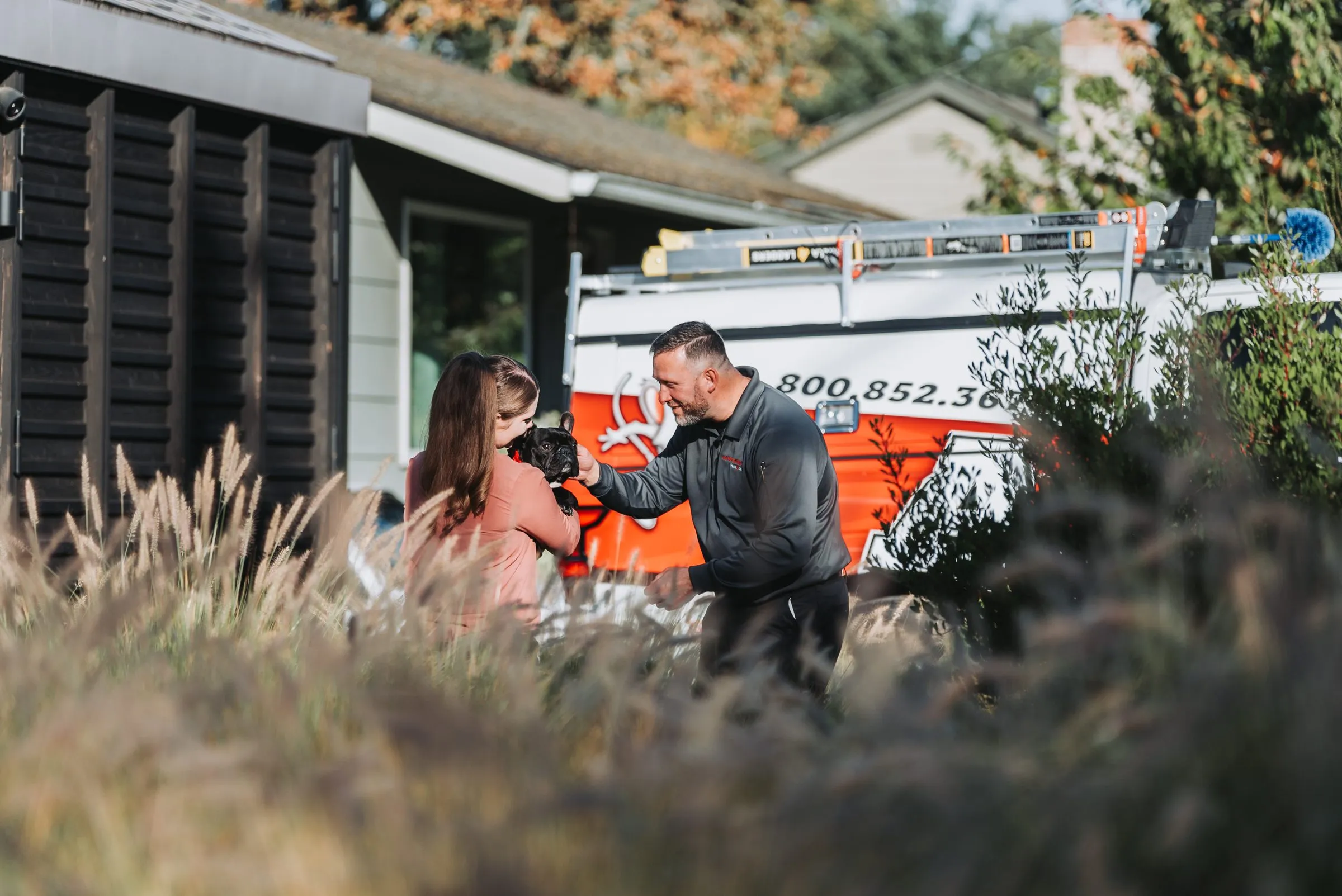 An A&A technician greeting a customer and her French bulldog, Lola, beside the service truck