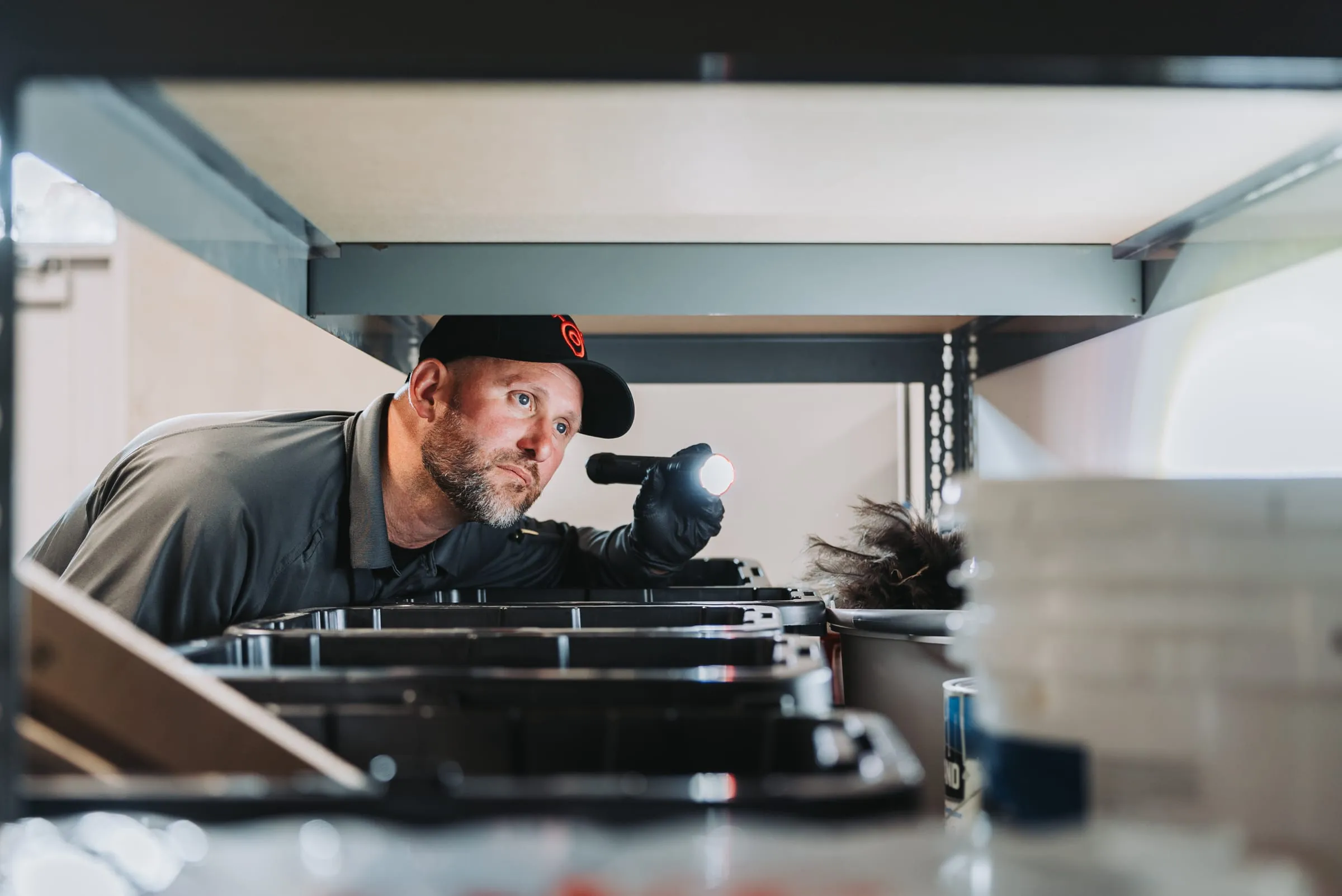 An A&A technician checking warehouse shelving with a flashlight