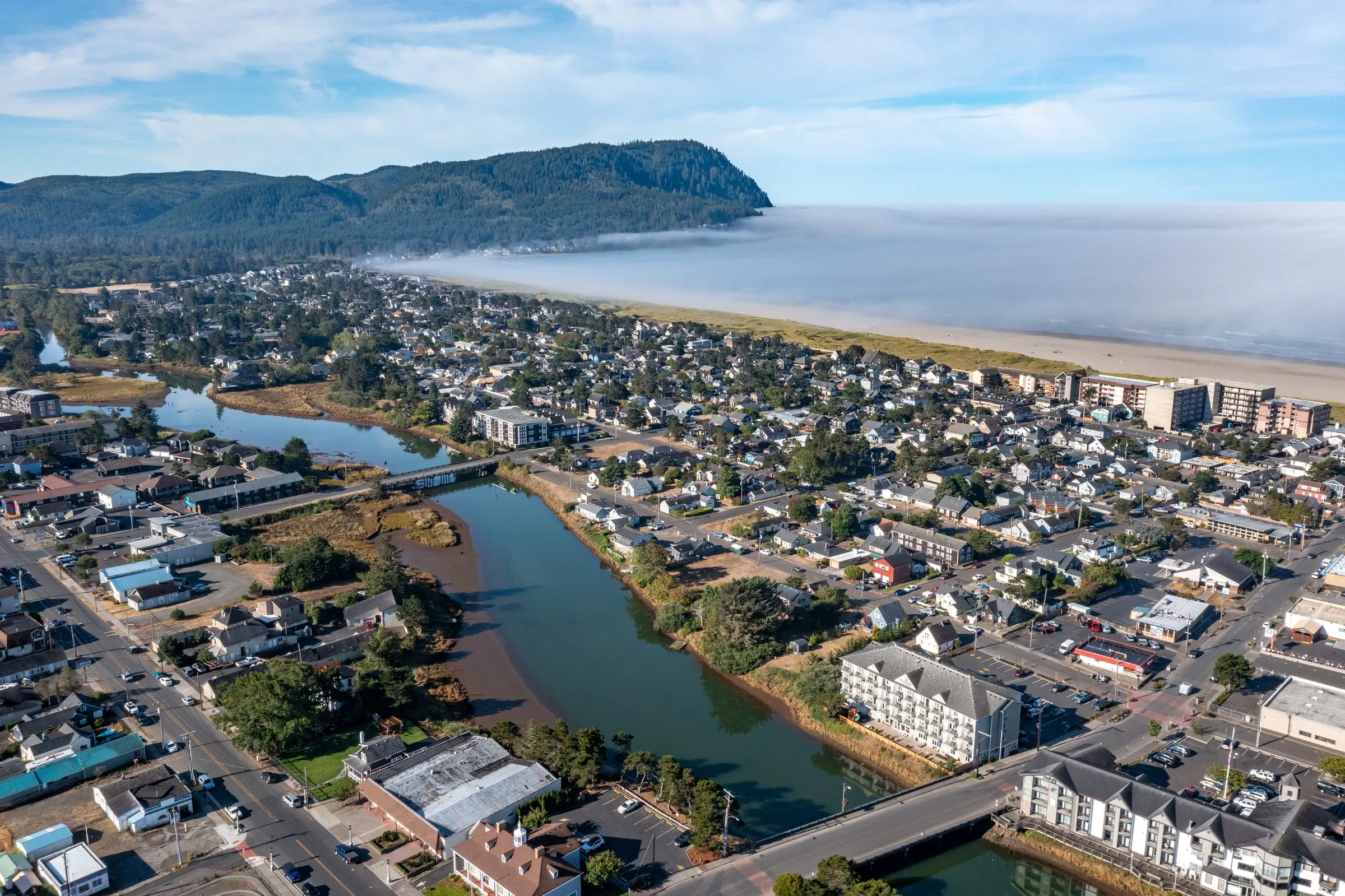 An aerial view of Seaside, Oregon, with the beach and a headland beyond the town