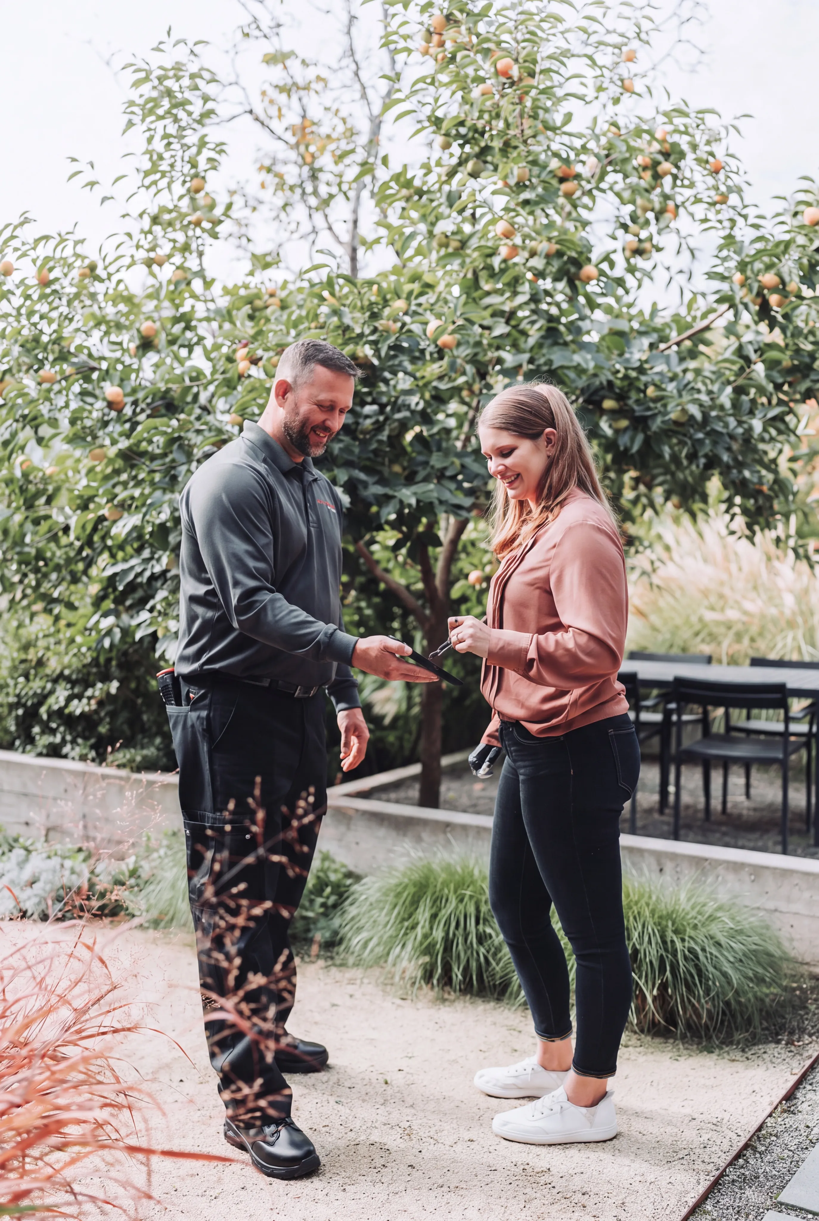 An A&A Pest Control technician talking through a service report with a customer in her garden