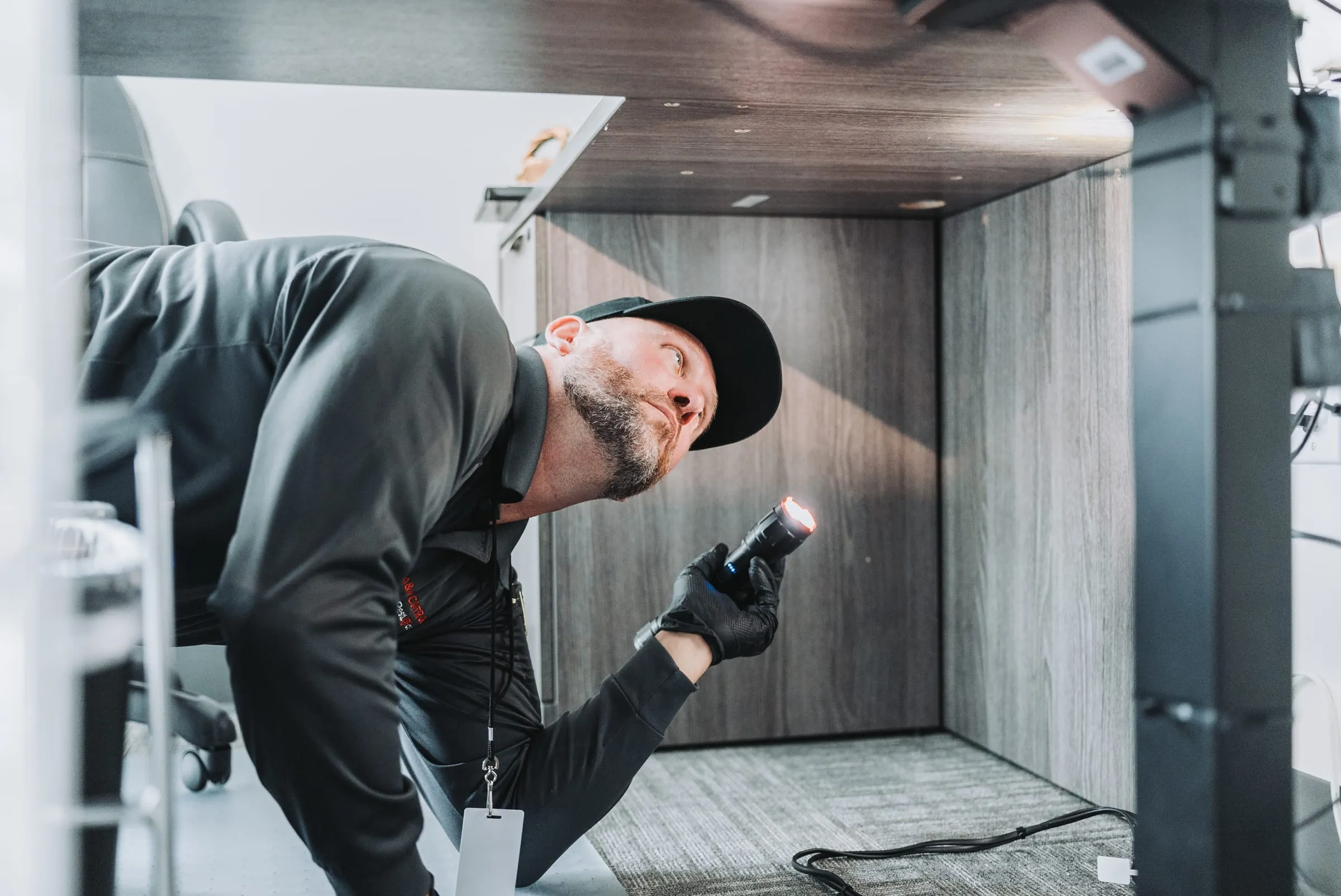 An A&A technician checking an empty cabinet with a flashlight